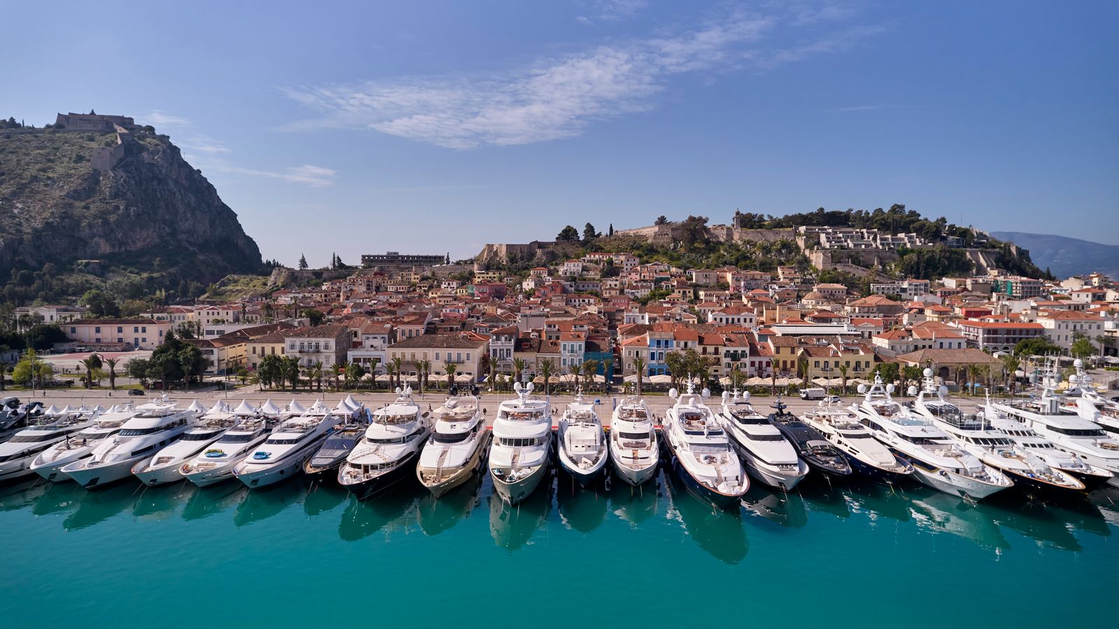 A luxury yacht anchored in a calm Mediterranean cove at sunset